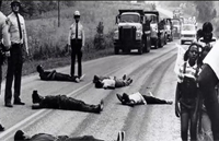 people lying down in front of trucks to protest a landfill